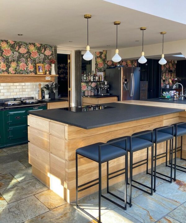 four gold lanesborough pendant lights suspended along the length of a wooden and grey kitchen island