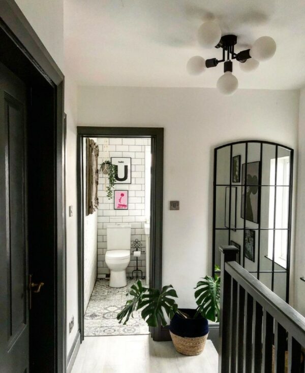 black connaught ceiling light at the top of a stairwell in a black and white hallway