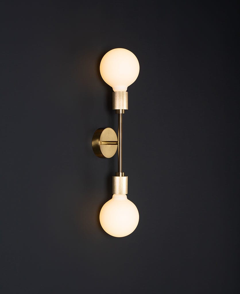 belgravia brass lit LED wall light against black wall