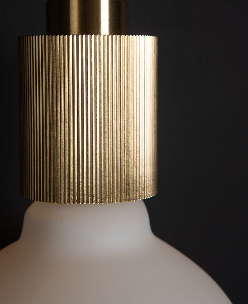 Brass Wall Light with frosted bulb against black background