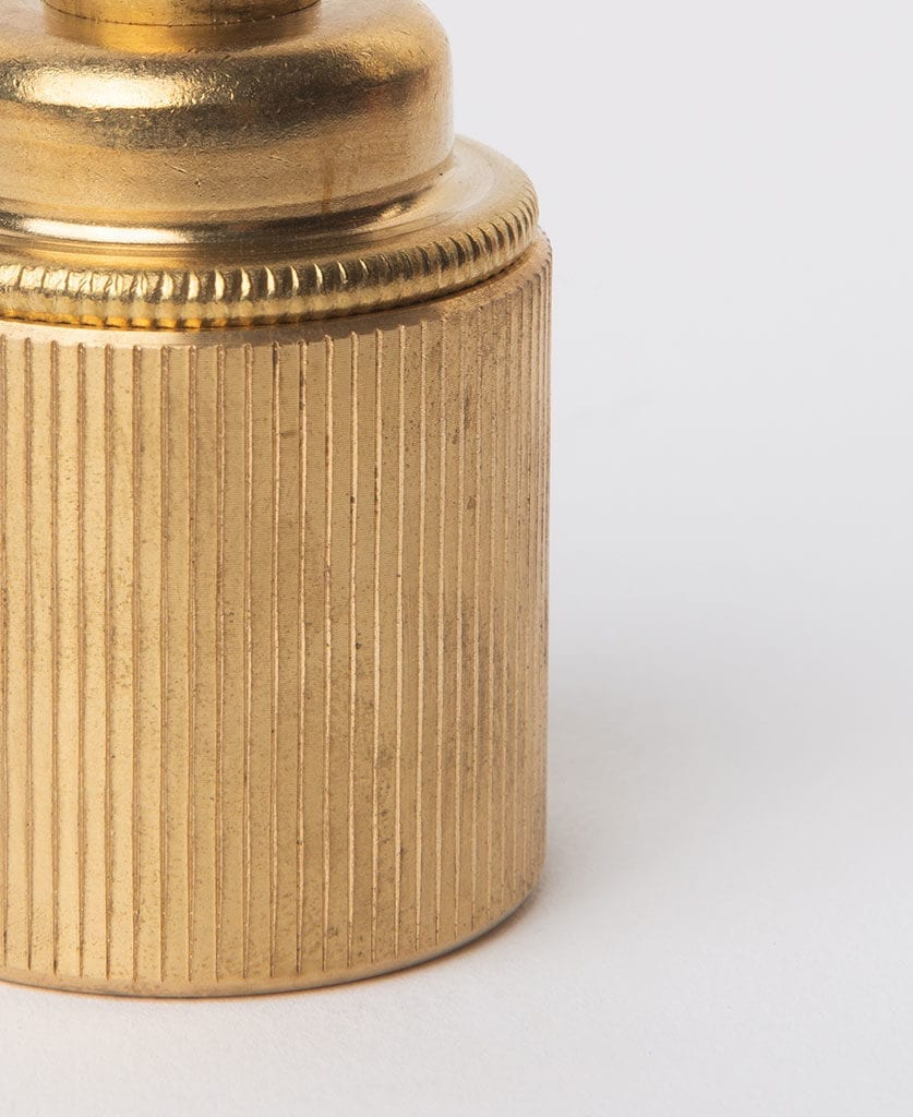closeup of raw brass ribbed bulb holder against grey background