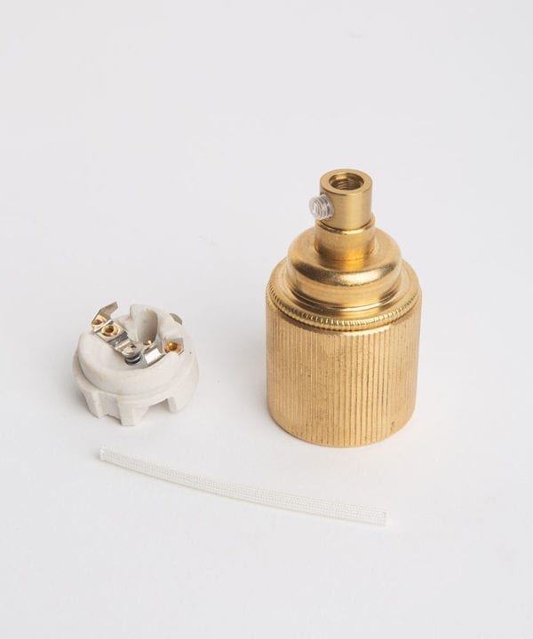e27 raw brass lamp holderwith ribbed detail with porcelain insert against white background