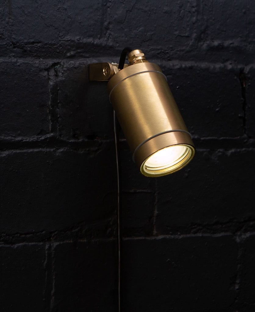 leonis raw brass against black brick wall