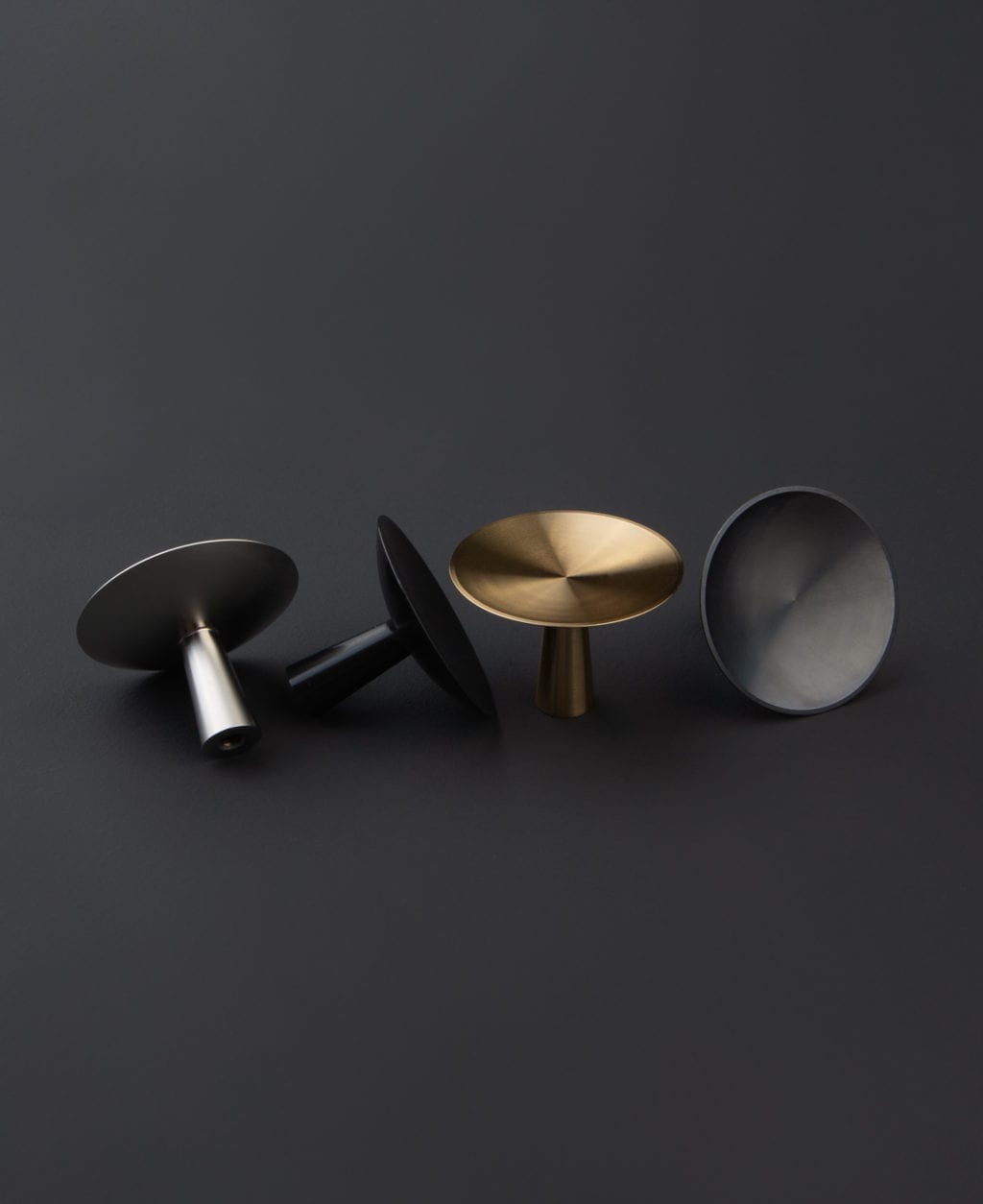 group shot of four rococo kitchen knobs in silver, black, gold and antique black against black background