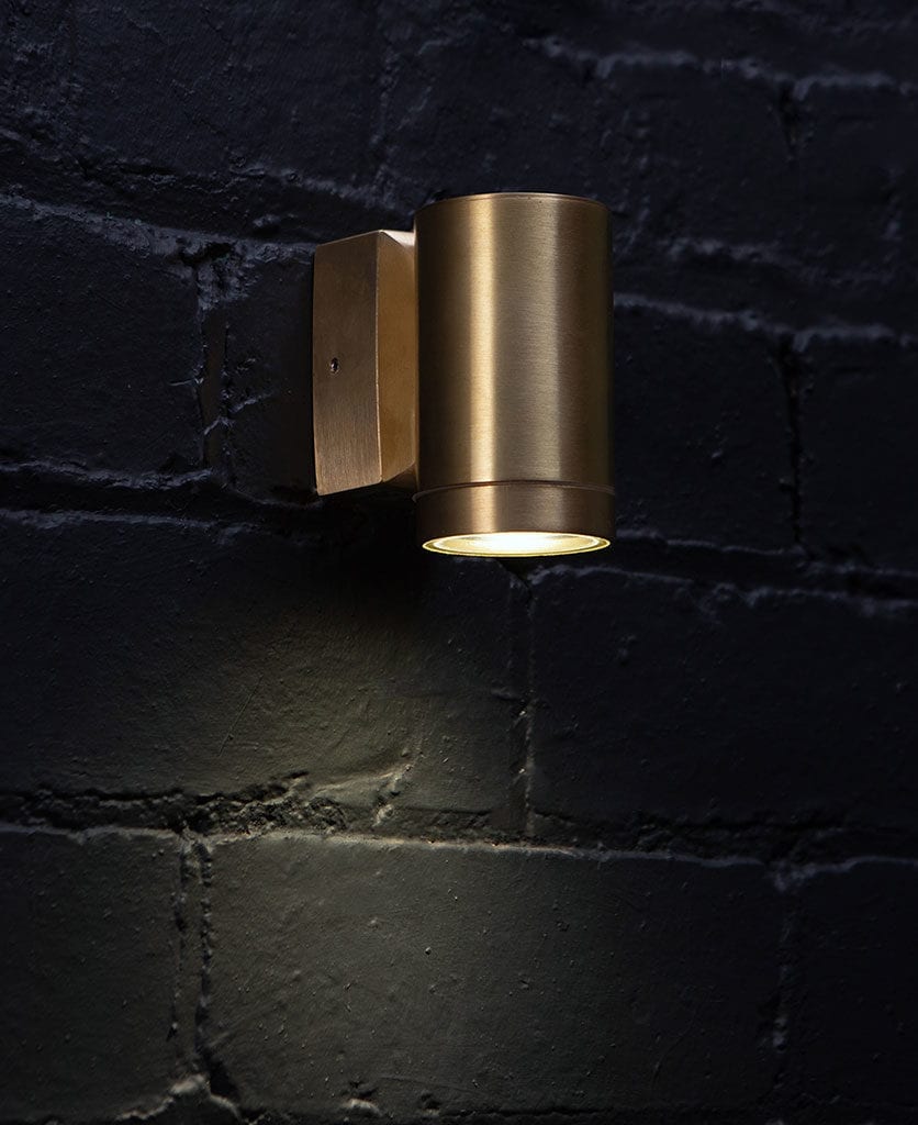 capella brass garden light against black brick wall