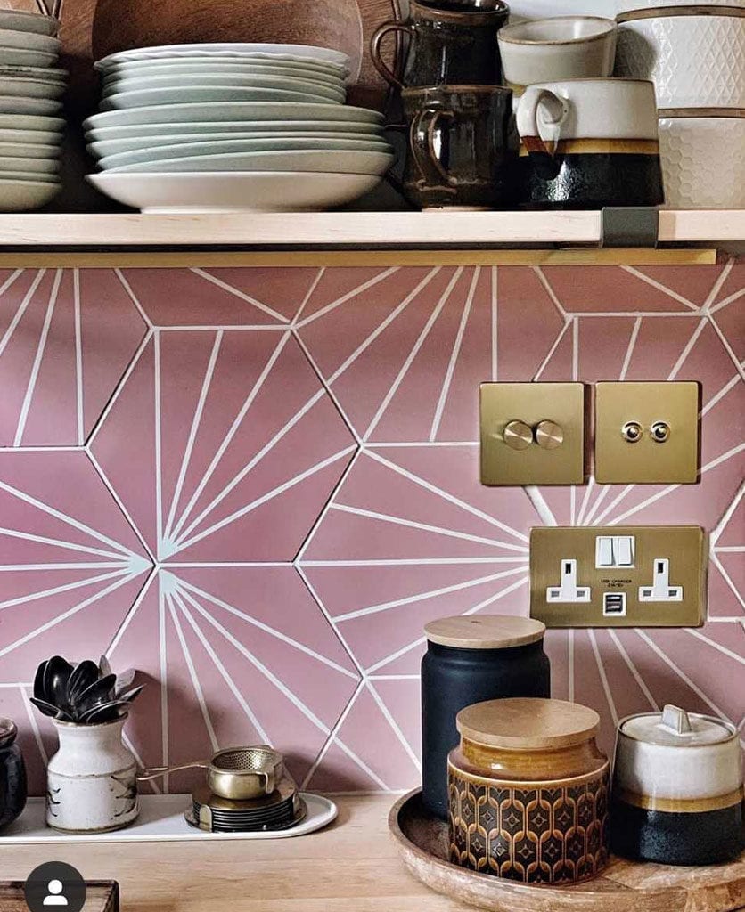 brass switches and sockets on pink and white tiled kitchen wall