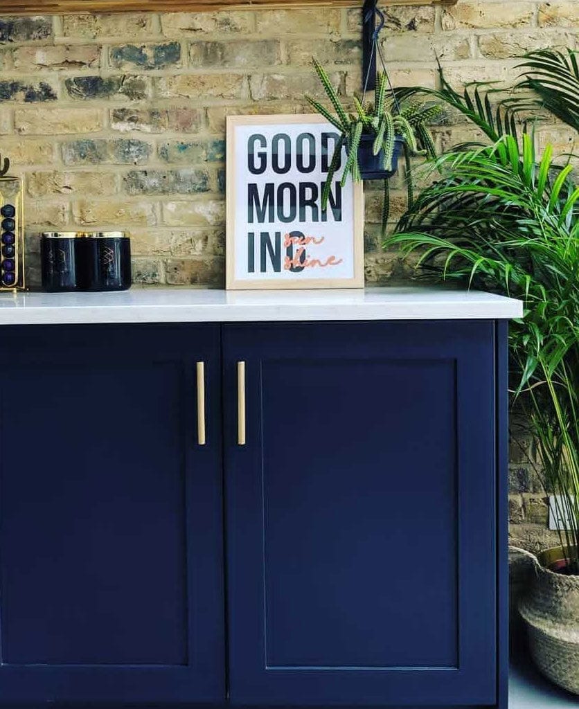 brass skyscraper handles on dark blue kitchen cupboards in an exposed brick kitchen