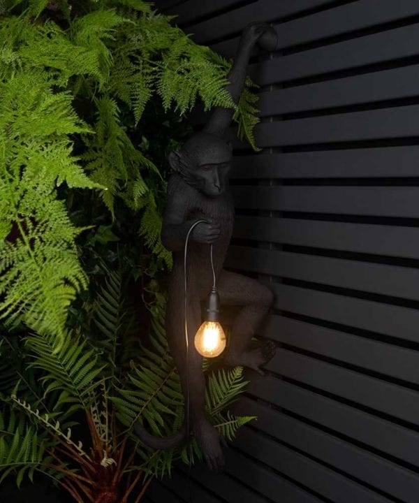 animal light louie outdoor monkey light suspended against black fencing