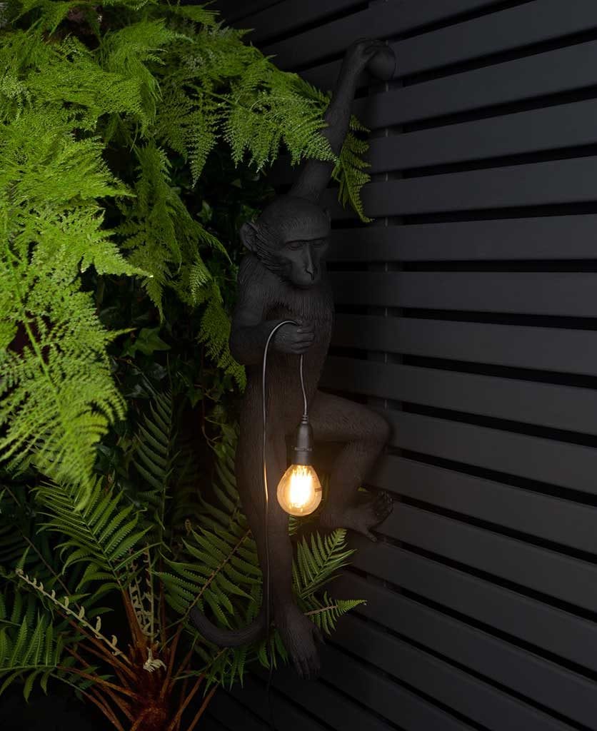 animal light louie outdoor monkey light suspended against black fencing