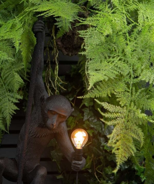 closeup of marcel monkey wall light surrounded by faux foliage