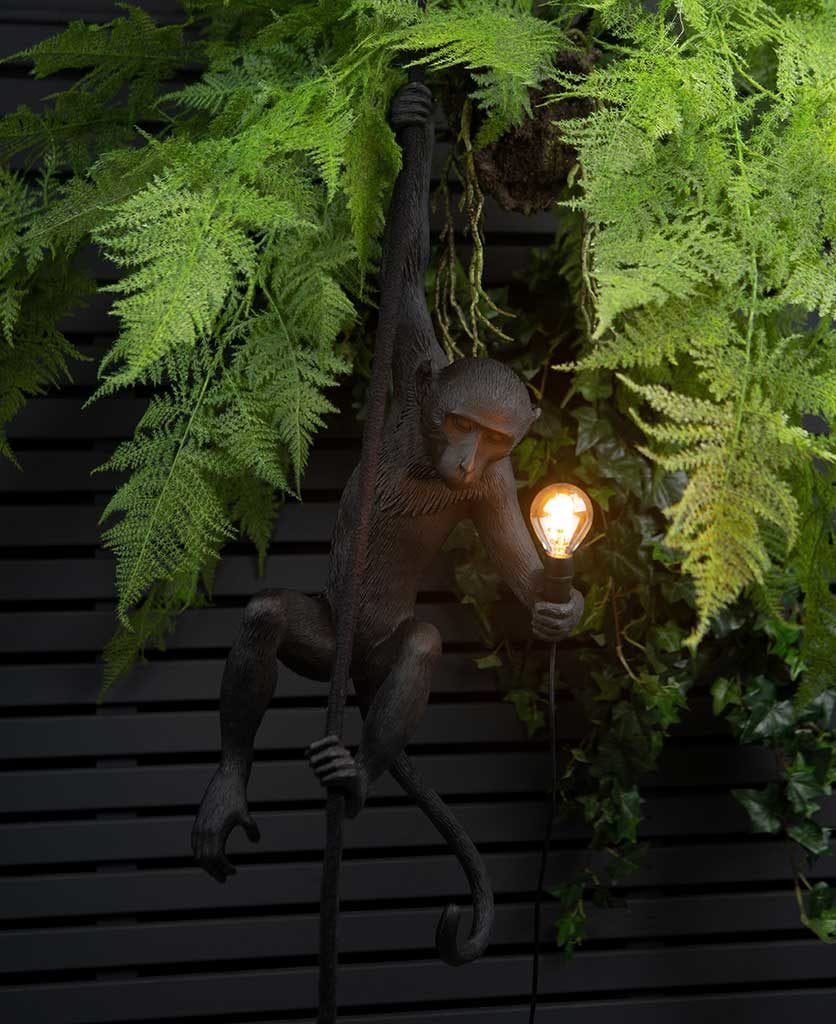 Marcel monkey outdoor light swinging besides some ferns