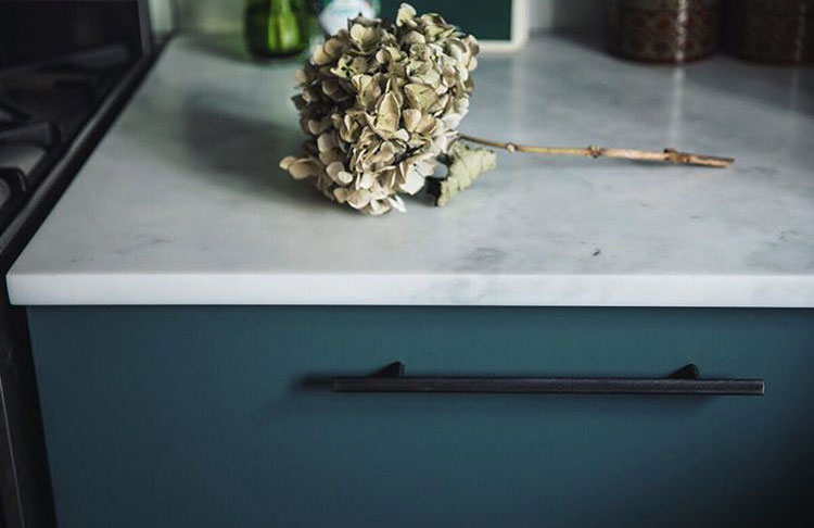 navy kitchen drawer with black skyscraper handle and white marble counter top