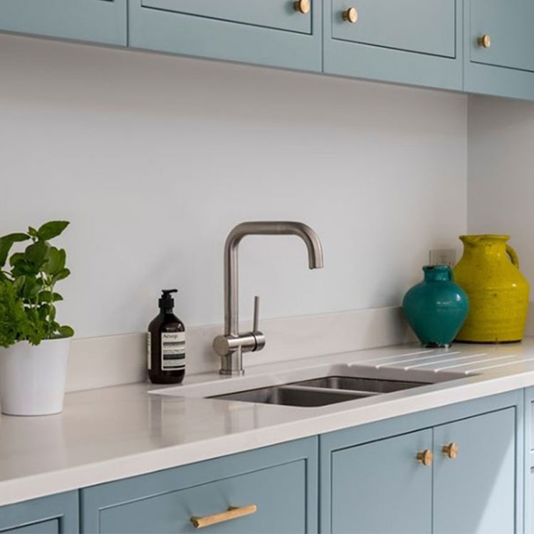 soft blue kitchen cupboards with brass door handles in white kitchen