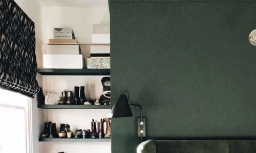 dark green painted wall with matching velvet headboard in a white and green bedroom