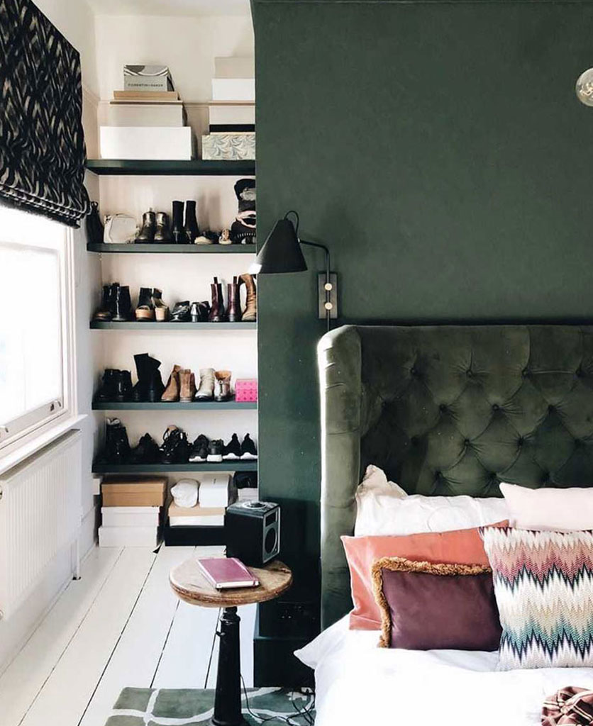 dark green painted wall with matching velvet headboard in a white and green bedroom