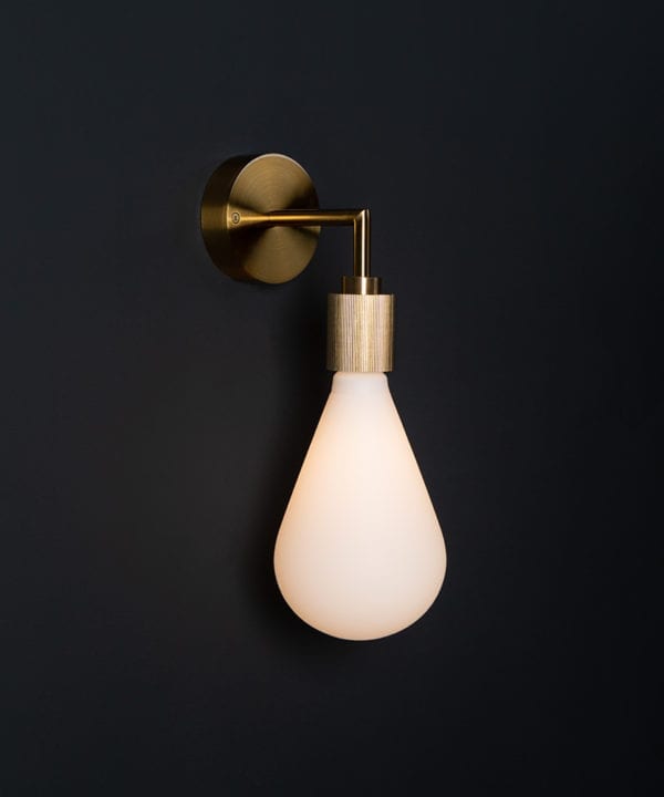 Grosvenor gold lit wall light fixture against black background