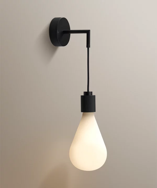 sleek bedside wall lamp with black metal, fabric cable shown with feature opaque teardrop bulb