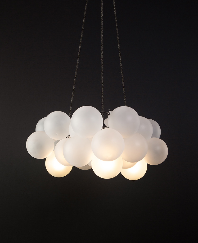frosted bubble chandelier pendant light featuring 24 frosted baubles & 5 bronze bulbholders suspended from textured fabric cable against a black wall