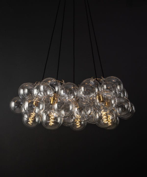 bubble glass chandelier with 40 glass baubles & 5 gold bulb holders suspended from black fabric cable against a black wall