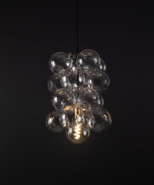 glass bubble light chandelier with 16 clear glass baubles and 1 gold bulb holder suspended from black fabric cable against a black wall