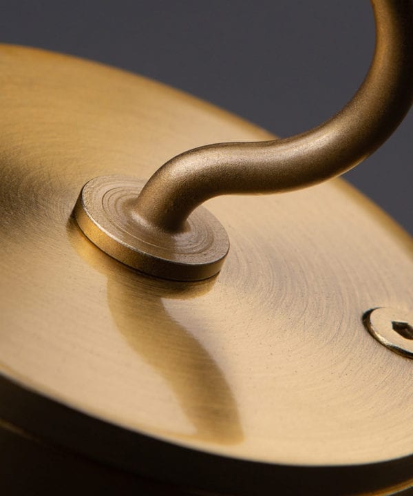 closeup of raw brass ceiling hook against black background