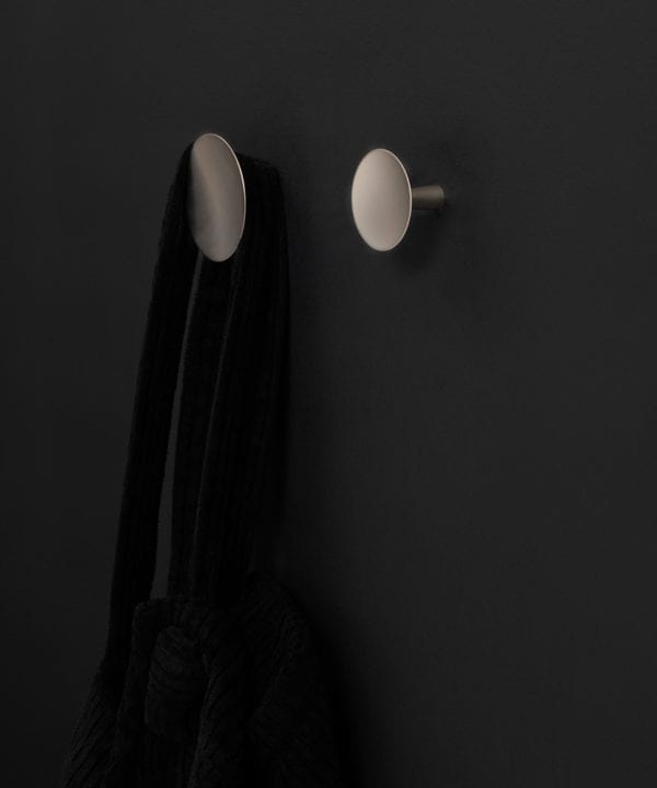 two silver Rococo kitchen hooks on a black wall