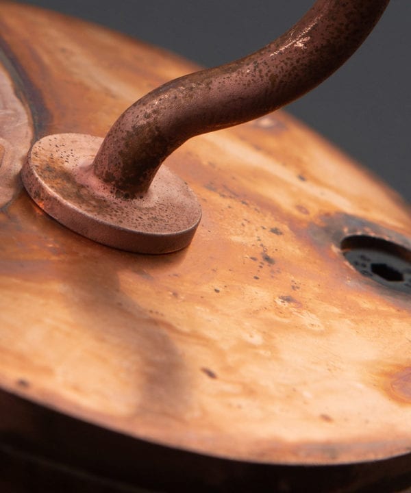 closeup of tarnished copper ceiling hook against black background