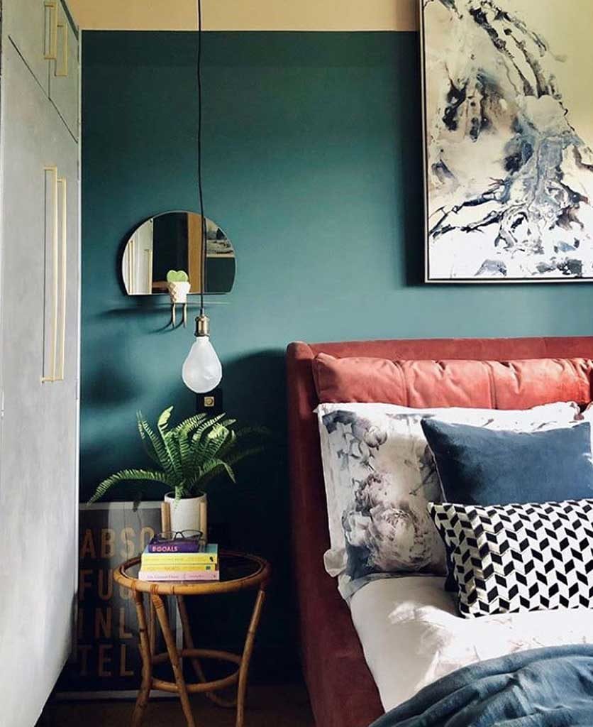 teal and white bedroom with suspended bulb bedside light and coral velvet headboard