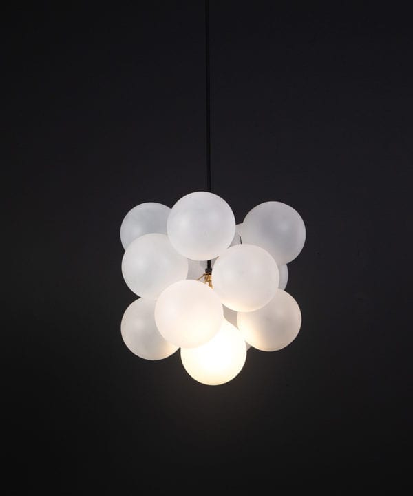 frosted glass bubble chandelier with 12 glass orbs and 1 gold bulb holder suspended from black cable against a black wall