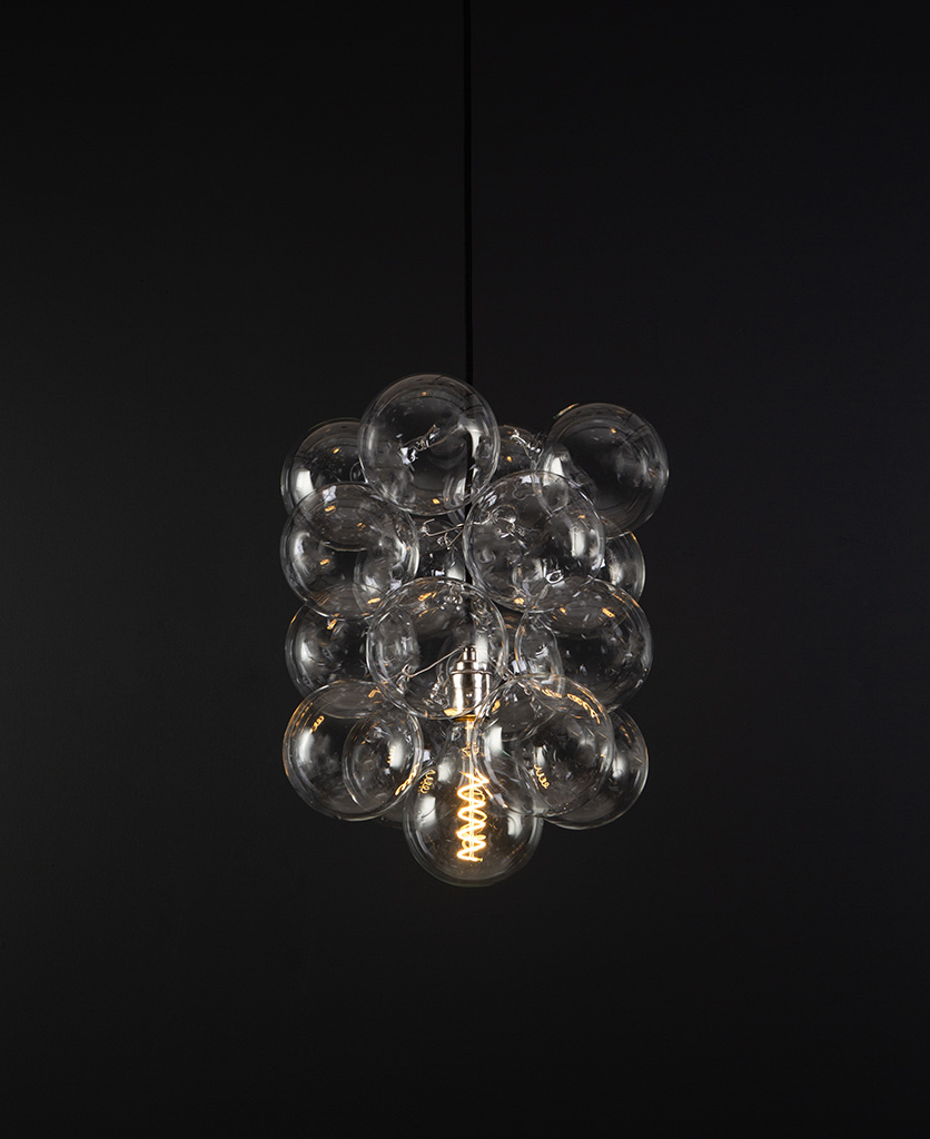 glass bubble light chandelier with 16 clear glass baubles and 1 silver bulb holder suspended from black fabric cable against a black wall