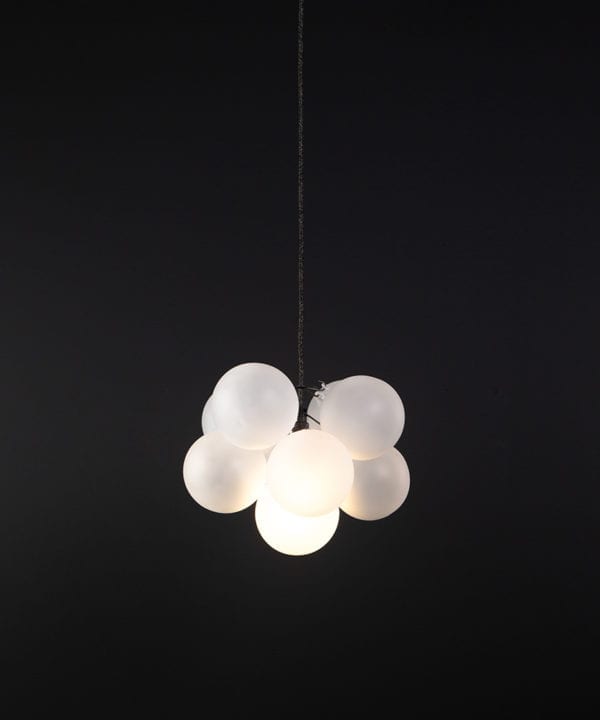 frosted glass bubble chandelier with 8 glass orbs and 1 bronze bulb holder suspended from textured cable against a black wall
