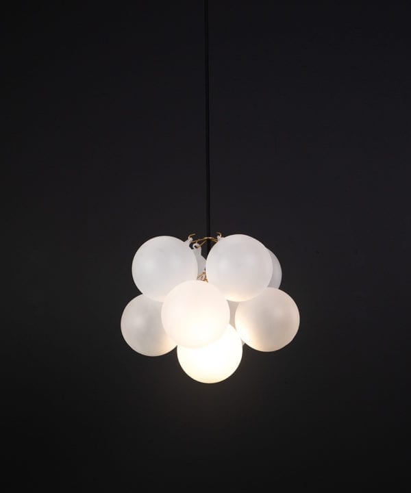 frosted glass bubble chandelier with 8 glass orbs and 1 gold bulb holder suspended from black cable against a black wall