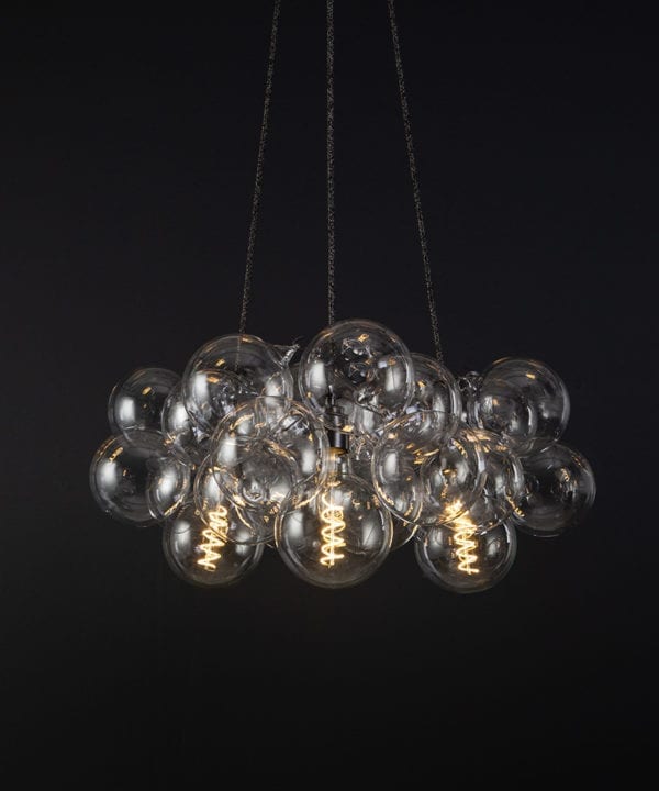 bubble pendant chandelier with 24 clear glass baubles and 3 bronze bulb holders suspended from textured fabric cable against a black wall