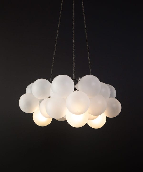 frosted bubble chandelier pendant light featuring 24 frosted baubles & 5 bronze bulbholders suspended from textured fabric cable against a black wall