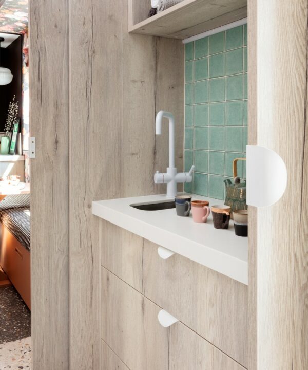 onda white ktichen handle installed on white doors and drawers in a wooden and mint green tiled kitchen