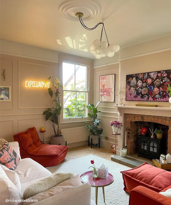 A medium frosted bubble chandelier in a pink living room with the cables draped over a ceiling hook.