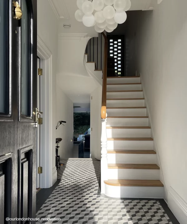 A medium frosted bubble chandelier in a hallway with a black door and a white staircase.