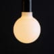 g95 aurora opal light bulb lit against black background