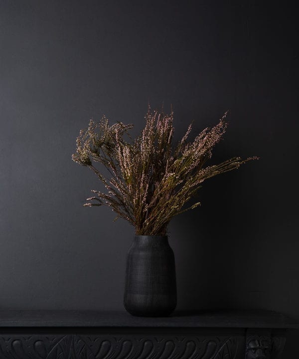 preserved heather bouquet in a black textured vase against a black background