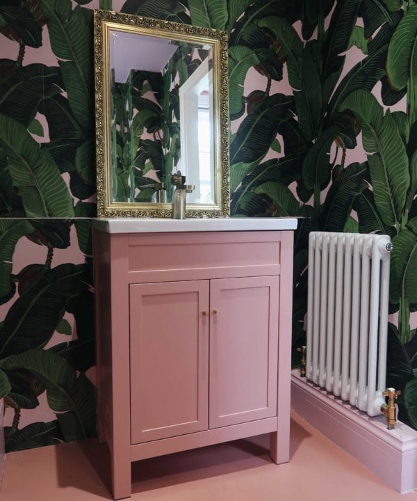 bathroom with pink and green botanical wallpaper, pink under sink cupboard with minimalist brass cupboard handles