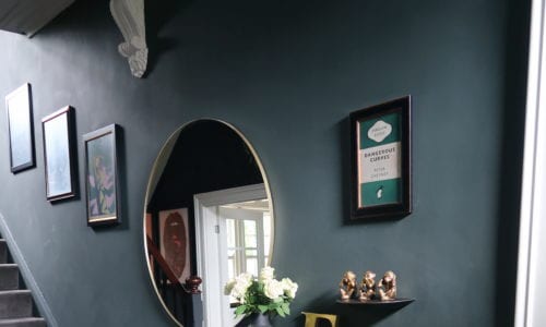 dark grey hallway with black storage unit and large round mirror