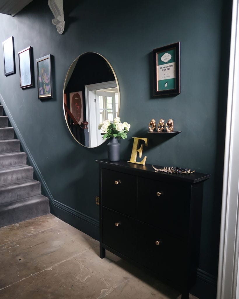 dark grey hallway with black storage unit and large round mirror