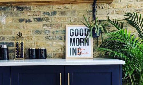 brass skyscraper handles on dark blue cupboards in an exposed brick kitchen