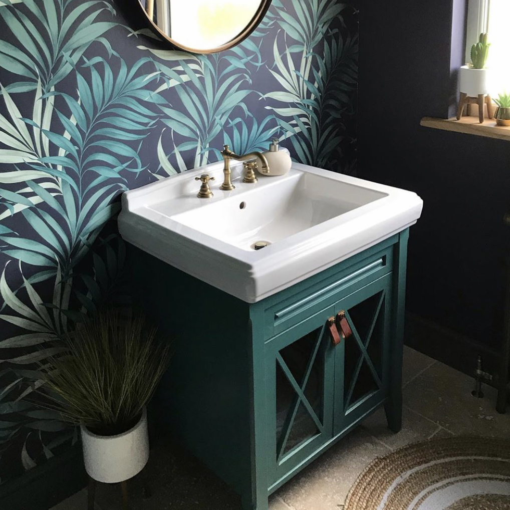 dark tan and gold magni handles on dark green under sink cabinet in a bathroom