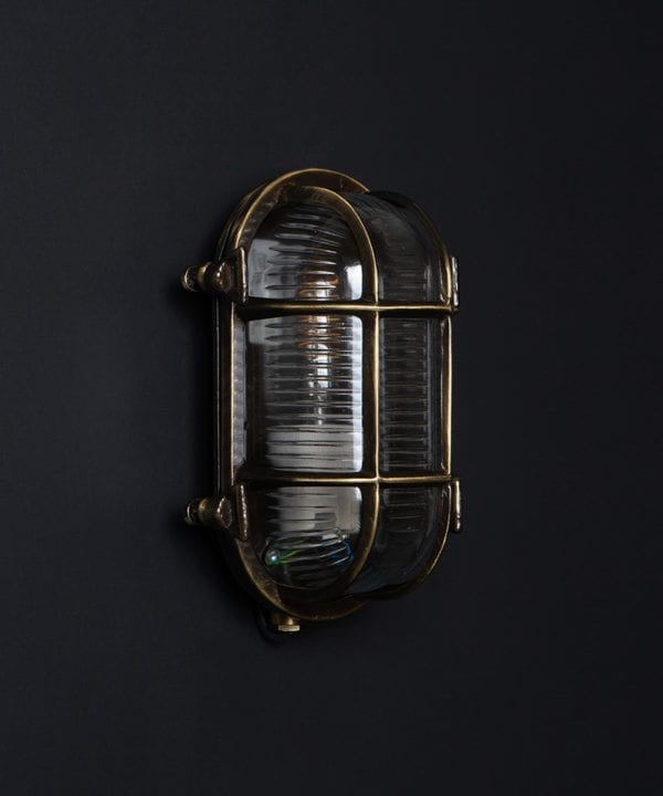 steve unlit aged brass bulkhead light with wingnuts against black background