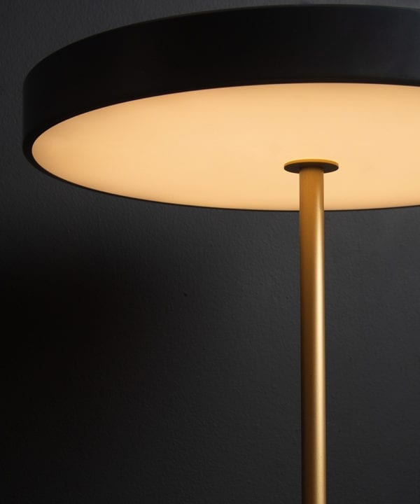 Close up of anthracite and gold umage asteria table lamp on black background switched on