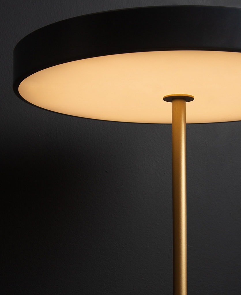 Close up of anthracite and gold umage asteria table lamp on black background switched on