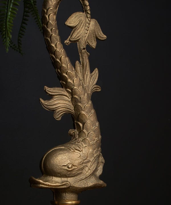 closeup of bellucci solid brass fish shaped pendant light against black wall