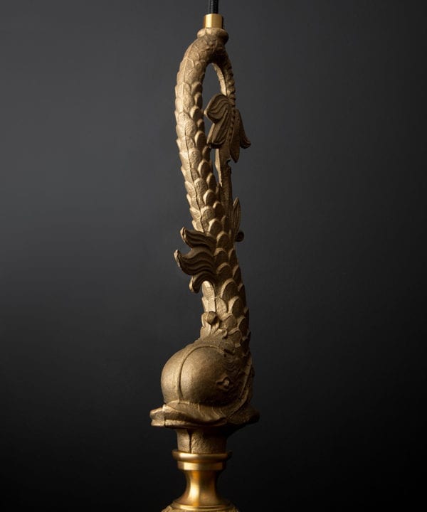 closeup of brass fish pendant light against black background