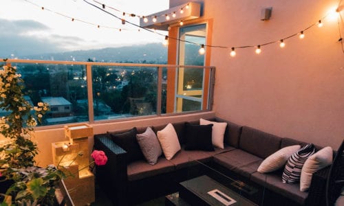 balcony at dusk with artificial grass, festoon lighting and rattan seating